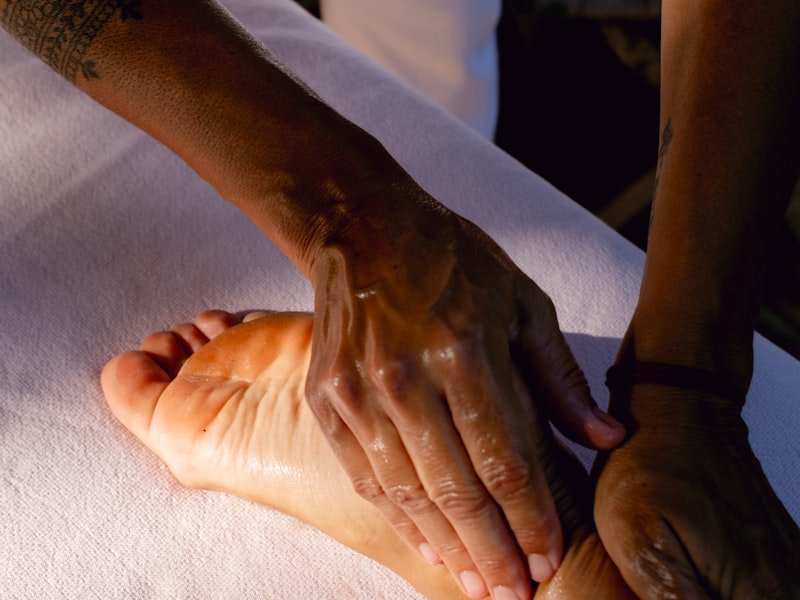 A therapist working the sole of a client's foot on a treatment surface